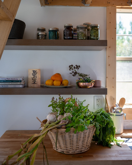 a kitchen with a basket filled with herbs and vegetables